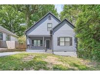 Charming home featuring a quaint front porch and traditional architectural details surrounded by mature trees and manicured lawn at 558 Elbridge Nw Dr, Atlanta, GA 30318