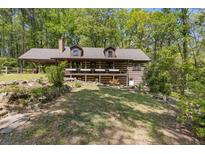Charming log home with a welcoming front porch, nestled among lush trees and beautiful landscaping at 2377 Pine Mountain Rd, Kennesaw, GA 30152