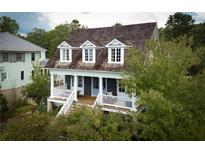 Charming home features a welcoming porch, dormer windows, and is surrounded by lush greenery at 10559 Serenbe Ln, Chattahoochee Hills, GA 30268