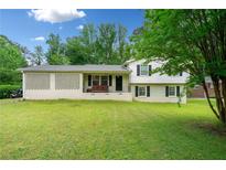 Charming home with a well-maintained lawn, a brick lattice accent, and a welcoming porch at 1448 Drayton Woods Dr, Tucker, GA 30084