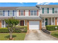 Traditional townhouse with a one-car garage, well-manicured lawn, and shrubbery at 7246 Alicias Way, Morrow, GA 30260