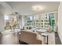 Bright, modern living room with hardwood floors, comfortable seating, and floor-to-ceiling windows offering city views at 20 10Th Nw St # 704, Atlanta, GA 30309