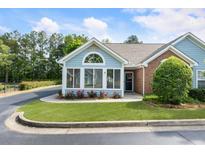 Charming home exterior with well-maintained landscaping, brick accents, and a cozy sunroom entrance at 15104 Harvest Ridge Ln, Alpharetta, GA 30022