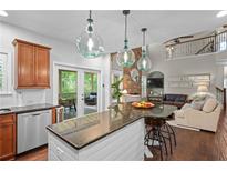 Open kitchen with granite counters, stainless appliances, and island seating overlooking the living area at 6250 Vista Crossing Way, Cumming, GA 30028
