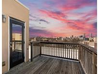 A spacious wooden balcony with a railing boasts beautiful city skyline views against a vibrant sunset sky at 791 Wylie Se St # 912, Atlanta, GA 30316
