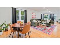 Bright living room with a wooden dining set, large window, and an olive green couch on a colorful rug at 4060 Haverhill Ne Dr # F, Atlanta, GA 30342