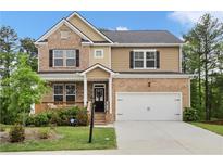 Charming two-story home featuring a brick and siding facade, a cozy front porch and a two-car garage at 1180 Trident Maple, Lawrenceville, GA 30045