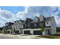 New construction townhomes featuring a two-car garage and dormer windows with modern white and dark siding at 208 Sharon Ln, Loganville, GA 30052