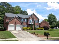 Charming two-story brick home with a well-manicured lawn, mature trees, and a two-car garage at 601 Hexham Ct, Suwanee, GA 30024