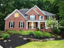 Charming brick home with a well-manicured lawn and lush landscaping at 1045 River Pt, Suwanee, GA 30024
