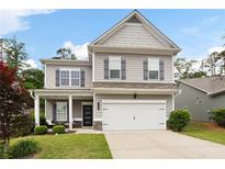 Charming two-story home featuring a well-manicured lawn, gray siding and shutters and a two-car garage at 129 Prominence Ct, Canton, GA 30114