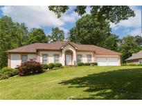 Charming one-story home with a well-manicured lawn and a two-car garage nestled among mature trees at 427 Picketts Lake Dr, Acworth, GA 30101