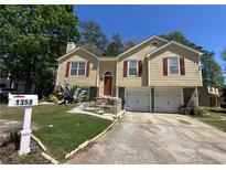 Charming split-level home with a two-car garage, well-maintained lawn, and inviting stone staircase at 1358 Stoneleigh Way, Stone Mountain, GA 30088