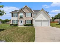 Charming two-story home with a manicured lawn, brick facade, and two-car garage on a sunny day at 510 Shire Ln, Fairburn, GA 30213