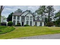 Two-story home with black and white trim, manicured lawn, and mature trees at 303 Sedgewick Trl, Lawrenceville, GA 30044