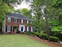 Charming two-story red brick home featuring black shutters and a well-manicured lawn and lush green landscaping at 1582 E Bank Dr, Marietta, GA 30068