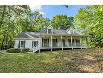 Charming two-story home with a large front porch and well-manicured lawn surrounded by mature trees at 4112 Willow Sw Walk, Lilburn, GA 30047