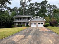Charming two-story home with a two-car garage and a well-maintained front yard, nestled among mature trees at 765 Corundum Ct, Stone Mountain, GA 30083