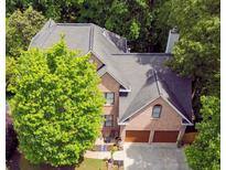 Aerial view of a beautiful brick home with mature trees and a two-car garage at 5105 Tynewick Ne Trce, Roswell, GA 30075