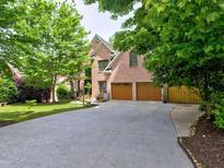 Charming brick home featuring a two-car garage, mature trees, and a well-maintained front yard at 5105 Tynewick Ne Trce, Roswell, GA 30075