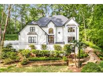 Stunning two-story white home with lush landscaping and a charming entrance, surrounded by mature trees at 900 Edgewater Nw Dr, Atlanta, GA 30328
