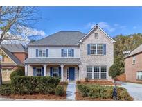 Charming two-story home featuring a brick facade, blue shutters, a welcoming porch, and well-maintained landscaping at 20 Daniel Crk, Sugar Hill, GA 30518