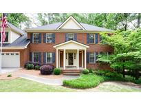 Charming brick two-story home featuring a manicured front lawn and a welcoming front porch at 1855 Vintage Dr, Snellville, GA 30078