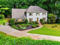 Charming two-story home with well-manicured landscaping, shutters, and a winding driveway at 1864 Gloucester Ct, Snellville, GA 30078