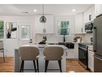 Bright kitchen features white cabinetry, stainless appliances, island with counter seating, and stylish pendant lighting at 904 Fairburn Nw Pl, Atlanta, GA 30331