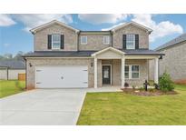 Charming two-story home features a brick facade, a two-car garage and a well manicured front yard at 6905 Winchester Pl, Fairburn, GA 30213
