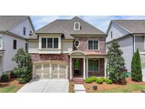 Charming brick home with manicured lawn, inviting front porch, and attached two-car garage at 919 Olmsted Ln, Johns Creek, GA 30097