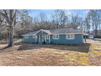 Charming single-story home features blue exterior paint, white trim, a landscaped yard and covered parking at 9588 Poston Rd, Jonesboro, GA 30238