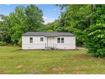 Charming single-story home with white painted brick, dark roof, green lawn and mature trees at 1350 Redford Se Dr, Atlanta, GA 30315