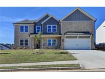 Inviting two-story home featuring a manicured lawn, attached two-car garage, and charming architectural details at 58 Longhorn Way, Auburn, GA 30011