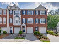 Charming brick townhome featuring a two-car garage, complemented by neat landscaping at 3194 Mill Springs Cir, Buford, GA 30519
