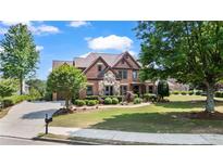 Beautiful brick home featuring a well-manicured lawn and meticulously landscaped front yard at 2400 Gants Hill Pl, Cumming, GA 30041