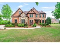 Beautiful two-story brick home with manicured lawn and stone accents at 2400 Gants Hill Pl, Cumming, GA 30041