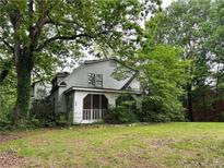 Quaint two-story home exterior featuring a screened-in porch and mature trees at 2413 Charleston Oaks Ln, Decatur, GA 30030