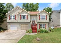 Charming split-level home featuring a manicured lawn, red shutters, and a two-car garage at 1647 Tunbridge Ln, Lawrenceville, GA 30043