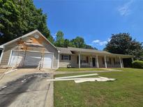 Charming ranch home with a covered front porch and a spacious front yard under a sunny sky at 65 King James Se Ct, Conyers, GA 30013