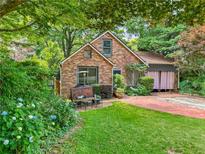Charming brick home with mature trees, lush landscaping, and a cozy front sitting area at 725 Brown Pl, Decatur, GA 30030