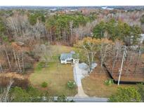 Aerial view of charming home on spacious lot surrounded by mature trees, with a winding driveway at 1892 Buford Dam Rd, Buford, GA 30518