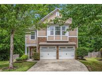 Charming two-story home featuring a two-car garage and a beautifully landscaped front yard with mature trees at 6155 Falls Landing Dr, Cumming, GA 30040