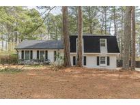 Charming two-story home with black shutters, white brick and mature trees at 7020 Camp Valley Rd, Riverdale, GA 30296
