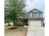 Two-story home features a two-car garage, complementary colored shutters, landscaping, and a well maintained lawn at 2166 Villa Spring Ct, Dacula, GA 30019