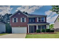 Charming two-story brick home with attached garage, landscaped yard, and covered front porch at 8256 Milam Loop, Fairburn, GA 30213