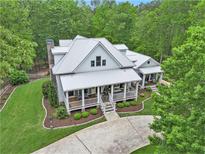 Aerial view of a beautiful farmhouse featuring a metal roof, a front porch, and a well-manicured lawn at 8901 Watkins Mill Rd, Winston, GA 30187