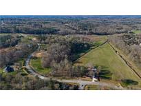 Expansive aerial view of the property, with mature trees, a large grassy field, and a winding driveway at 3721 Mason Creek Rd, Winston, GA 30187