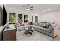 Spacious living room featuring a large sectional sofa, ceiling fan, and oversized windows overlooking mature trees at 1070 Harper Dr, Alpharetta, GA 30076