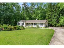 Charming single-story home featuring a well-manicured lawn and a driveway surrounded by lush greenery at 1824 Mcclung Rd, Hiram, GA 30141